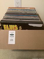 Cardboard box containing approximately 50 standing vinyl LPs, front sleeve Elvis self-titled visible