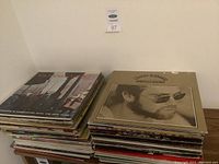 Stack of assorted vintage LP vinyl records from a side view showing multiple album spines and covers