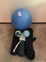 All items arranged on carpet, showing large blue exercise ball with size 70 tag, two small mini exercise balls, yoga mat rolled with strap, and two black carrying bags.