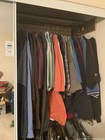 Closet rod holding multiple men's collared shirts of various colors and patterns hung on hangers.