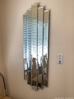 Full frontal view of the vertical multi-panel wall mirror mounted on a wall, showing all five panels and their varying heights.