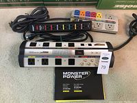 Two Monster Power branded power bars including HTS 1000 MKII and AV 635, showing front and top views with power cords, labels, and switches.