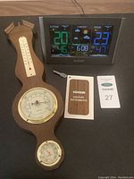 Photo of Springfield wooden wall-mounted weather instrument with thermometer, barometer, and hygrometer next to La Crosse Technology digital weather station and tags