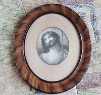 Full view of oval framed engraving showing polished wood frame, beige matting, and glass over the image.