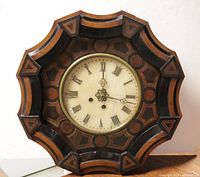 Full view of the octagonal inlaid wood wall clock with Bull's Eye pattern and Roman numeral dial