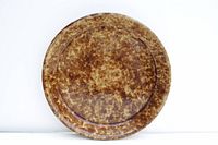 Top view of round brown spongeware pottery pie plate showing mottled sponge pattern and flat base inside.
