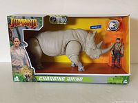 Front view of boxed Jumanji Charging Rhino action toy with small human figure visible inside.