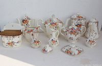 Wide view of the entire Moriyama Mori-Machi hand-painted porcelain serving ware set showing all pieces including sugar, salt, ginger containers, teapots, creamers, and decorative bottles.