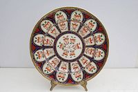 Full front view of the circular wall plaque showing floral pattern and decorative blue, red, and gold accents.