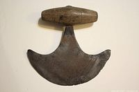Front view of ulu showing curved iron blade with pointed tip and wooden handle connected by brass fitting