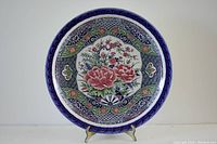 Front view of the charger plate showing colorful floral and bird design with patterned border.