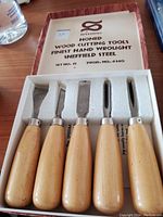 Boxed set of five wooden-handled wood cutting tools with honed Sheffield steel blades.