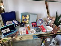 Photo showing entire lot including cloisonné sets, incense holders, talismans, bowl, whistle, bookmarks, umbrella and trinket box on shelf