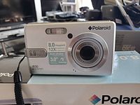 Front view of silver Polaroid 8.0 megapixels digital camera with 12x total zoom and 3.0 inch screen.