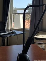 Black desk lamp on wood surface near window and black desk.