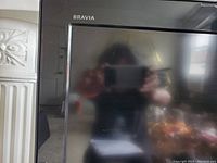 Close-up front view of Sony Bravia TV with Bravia logo on top left of bezel and reflective screen.