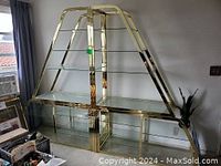 Front view of gold-finish metal display stand with multiple glass shelves