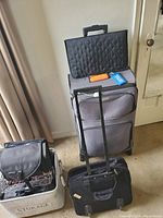 Photo showing assortment of suitcases and bags including large suitcase with telescoping handle, quilted black briefcase, and black camera bag inside storage basket.