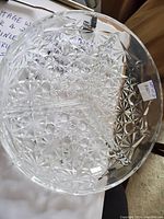 Top view of a large glass plate with geometric star pattern and intricate cut design, tagged $8.00.