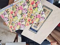 Three photo albums, visible floral printed album on top, Holson cream colored album with 200 slots, and white box album with dove image.