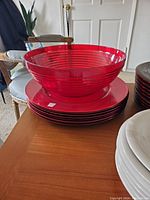 Red plastic chargers stacked with a large matching red bowl on top, ribbed design visible.