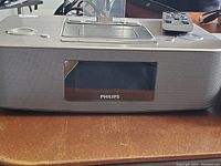 Philips iPad/iPhone/iPod docking station and alarm clock radio showing front panel and remote control on table