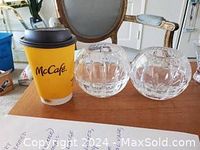 Two clear crystal spherical vases placed next to a McCafe cup for size reference on a wooden table.