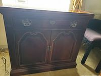 Full view of the front of the vintage mahogany flip top server showing detailed carved Chippendale style front paneling and brass hardware drawer pulls and door handles.