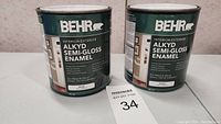 Two cans of Behr Alkyd Semi-Gloss Enamel paint for interior and exterior use, white color, 931ml each.