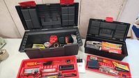 Two open tool boxes showing various tools inside including a tape measure, screwdriver set, flashlight, caulking gun, utility knife, wrench, and hand saw.