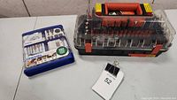 Blue plastic case with 162-piece Dremel accessory set and separate black and orange case with various drill and tool bits.