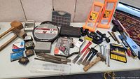 Full overview of lot including wooden mallets, metal clamp tool, screwdrivers, tape measures, clamps, solder spool, and other hardware tools and parts.