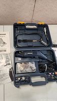 Rotary tool kit case open showing rotary tool, flexible shaft, accessories in compartments, instruction manuals.
