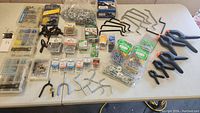 Full spread of items on white table including screws, hooks, clamps, bolts, anchor kits and related hardware