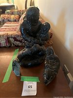 All three Indigenous sculptures displayed on wooden table with auction tag visible.