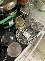 Top view showing assorted clear glass and crystal dishes, a tall vase, small pedestal dishes, and a gold-tone basket with handle and lid.