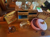 Wooden jewelry box with four drawers open and closed, lattice doors opened showing blue fabric lined drawers, various glass and ceramic jewelry holders placed on and around the box.