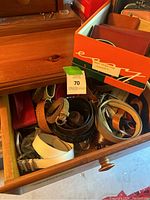 Drawer containing assorted women's belts in various colors including white, brown, black, braided styles.