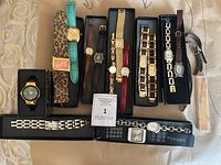 All watches arranged in trays and on surface showing gold-tone and silver-tone cases, leather and metal straps