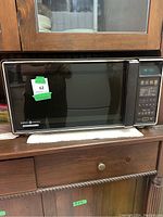 Front view of the GE Spacemaker 2 microwave oven showing its black door, stainless steel trim, and digital keypad with clock display.