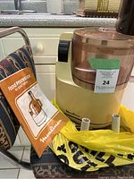 Full view of beige Moulinex food processor showing food processing bowl, control lever, and brand name on the base, photographed on a patterned chair with a user manual booklet.