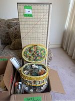 Box containing a fabric cutting mat and a yellow floral-patterned sewing kit basket with various sewing supplies inside.