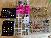 Overview of multiple organizer trays filled with assorted vintage costume earrings including studs, hoops, dangles, and clip-ons