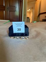 Five gold rings displayed in front of auction bid card in box