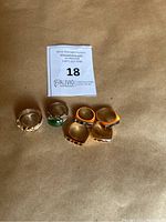 Top view of all six rings arranged in two rows on a brown surface with auction lot tag visible.