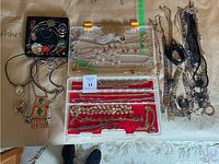 Overview of entire lot showing multiple trays and loose pile of necklaces