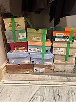 Photo showing stacked women’s shoe boxes from various brands including Easy Spirit, ECCO, Clarks, Van Eli, Trotters, Francesca and more. Boxes are mostly size 9 and 10.