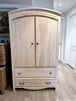 Front view of the closed armoir highlighting the design, doors with handles, and two bottom drawers.