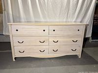 Front view of six-drawer dresser showing drawer hardware and wood finish with some scratches on top.