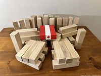 Display of over 50 natural wooden blocks standing and stacked with three colored blocks in the middle; two red and one white with Canadian flag.